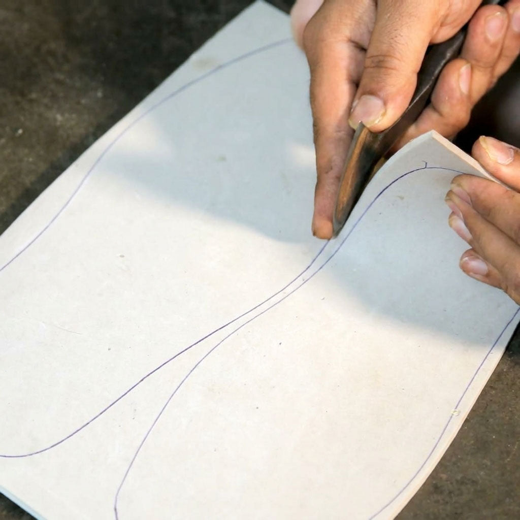 Master artisan hand-cutting premium foam for inner padding of BERA luxury footwear using traditional shoe making tools.