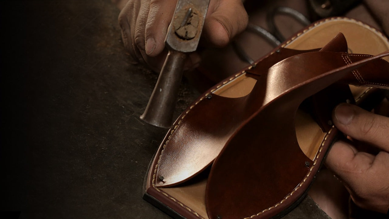 Image of a man crafting a pair of brown Pakistani footwear