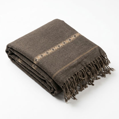 Neatly folded men's dark charcoal brown wool shawl featuring a subtle beige woven geometric border and fringed tassel ends   